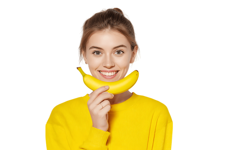 Young woman holding a banana like a smile. Healthy eating, happiness concept.