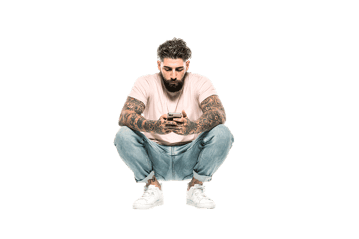 Man with tattoos sits on floor using smartphone